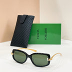 Black sunglasses with green-tinted lenses and gold-tone accents, with a black case