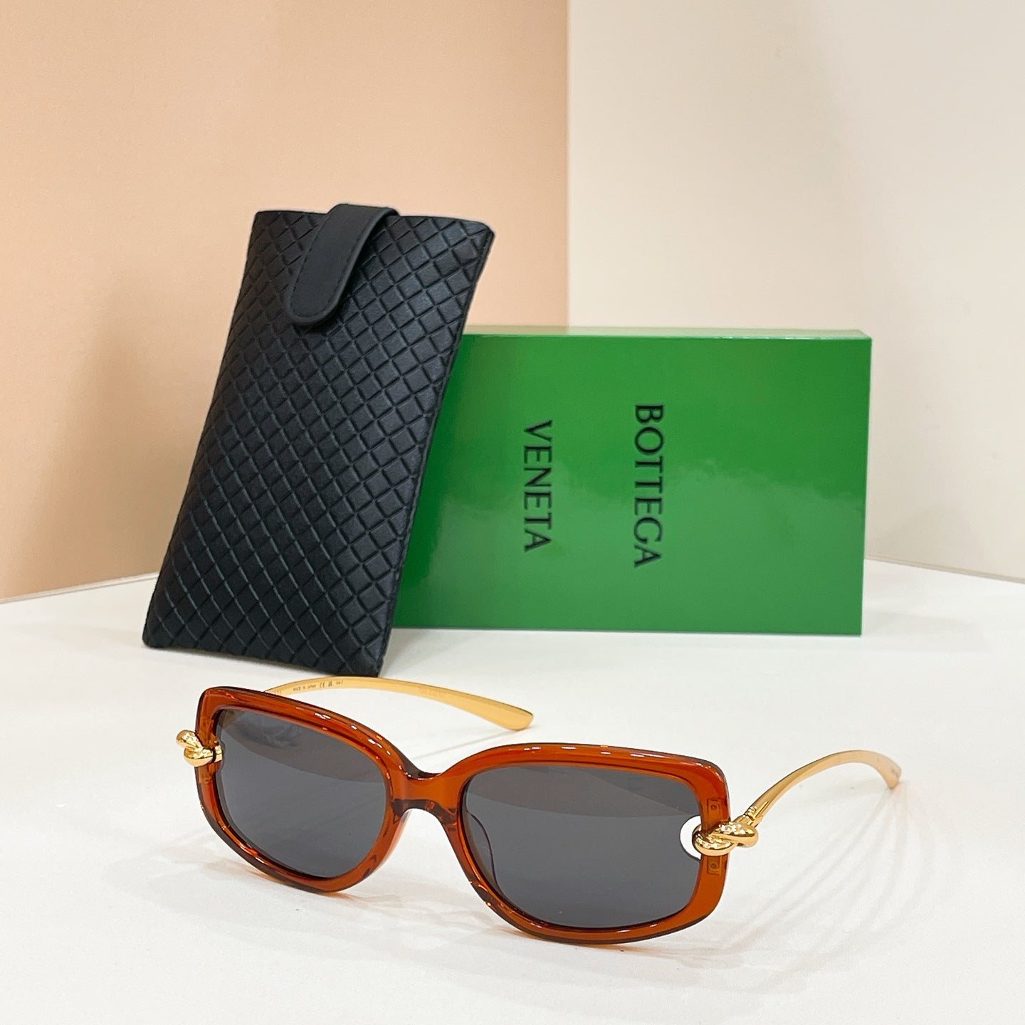 Orange-brown sunglasses with dark lenses and metal arms, paired with a black case