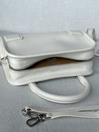 White leather handbag with top zipper, brown lining, and crossbody strap