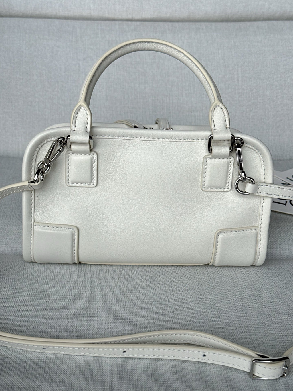 White leather handbag with top handles, front panels, and detachable shoulder strap