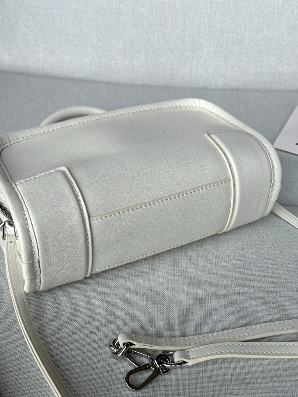 White leather handbag side view with stitched trim and silver zipper hardware