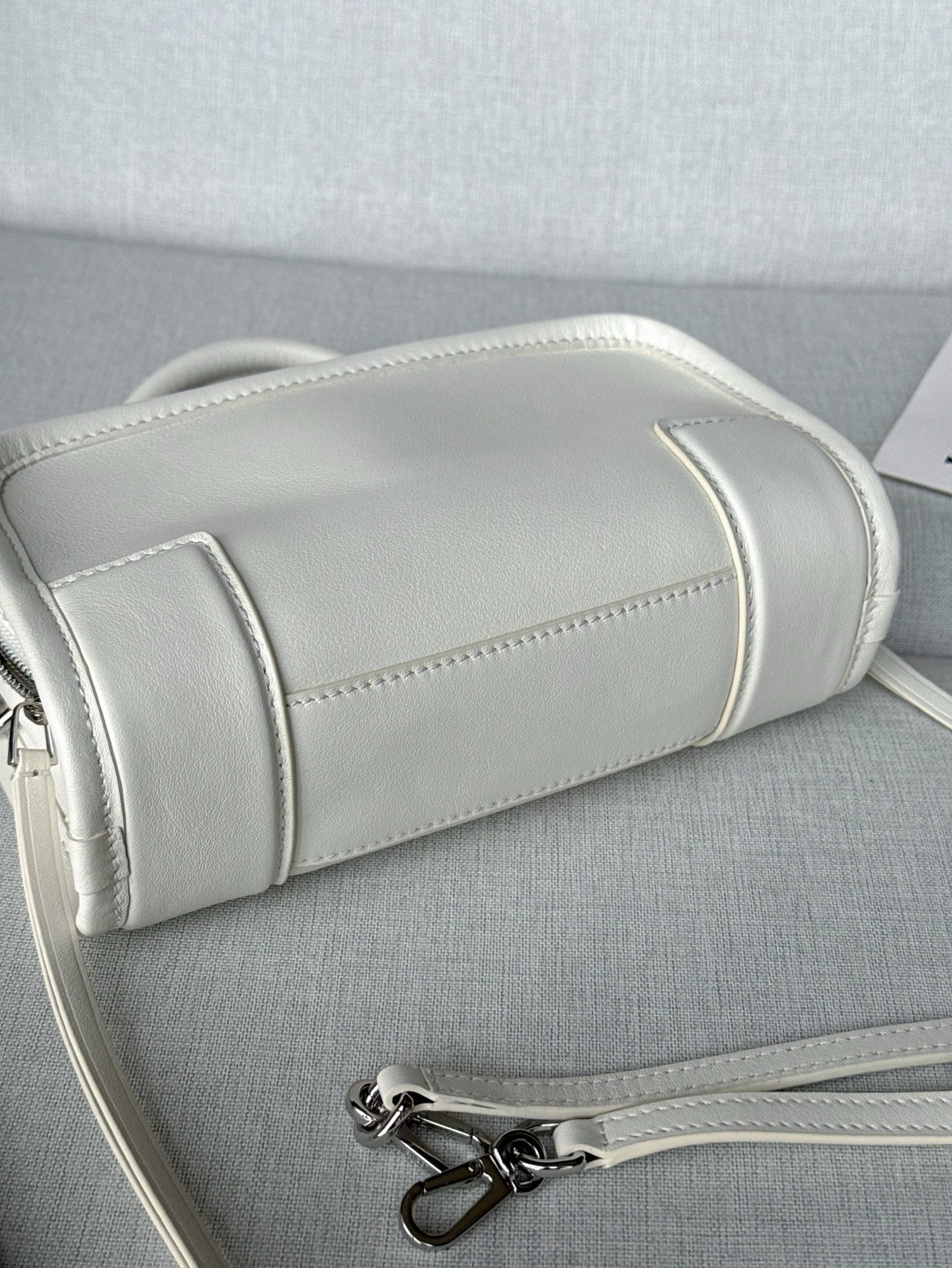 White leather handbag side view with stitched trim and silver zipper hardware