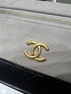 Chanel bag close-up of gold logo on light gray quilted leather with black trim