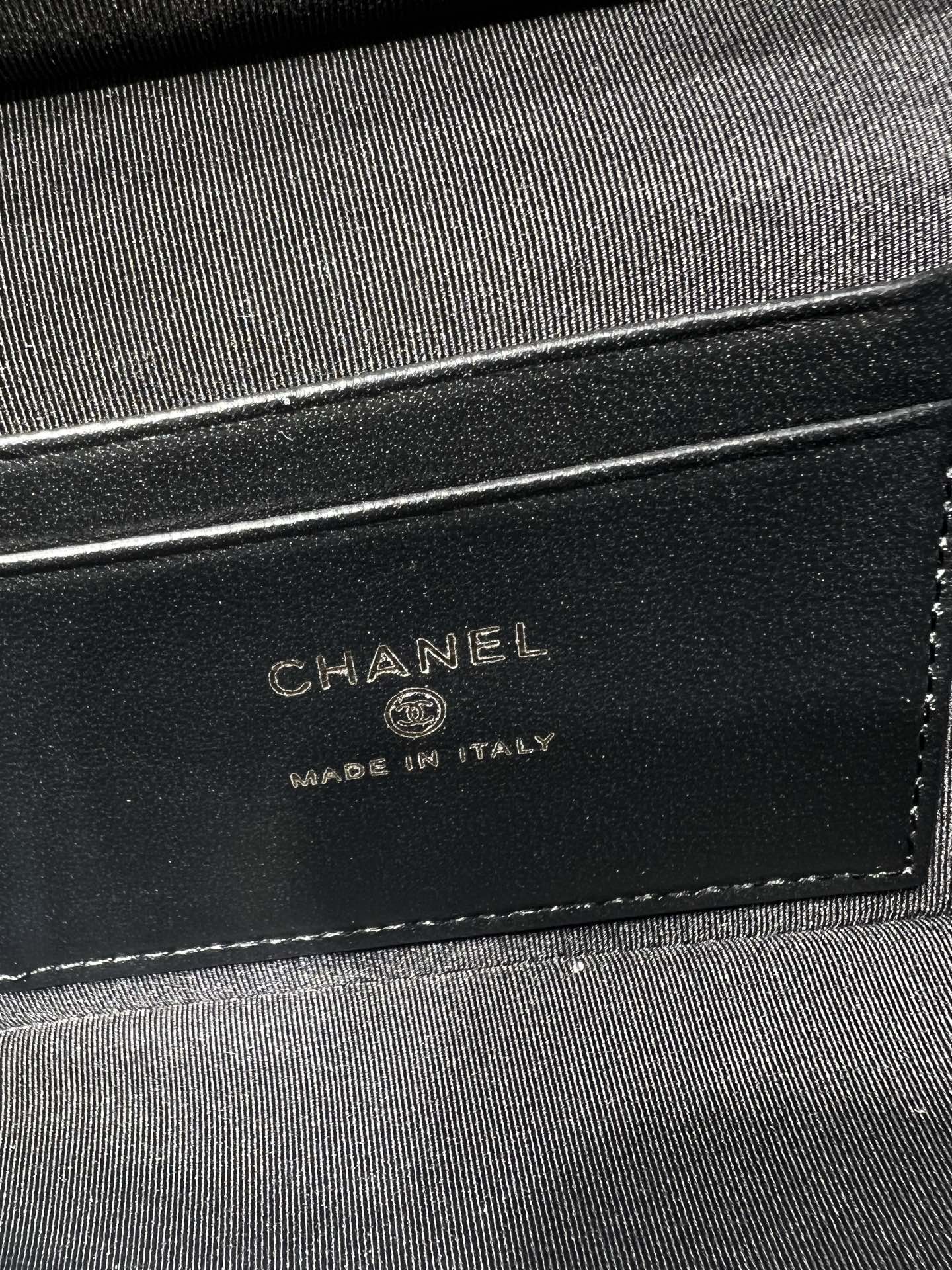 Chanel bag lining label on black fabric showing CHANEL and Made in Italy