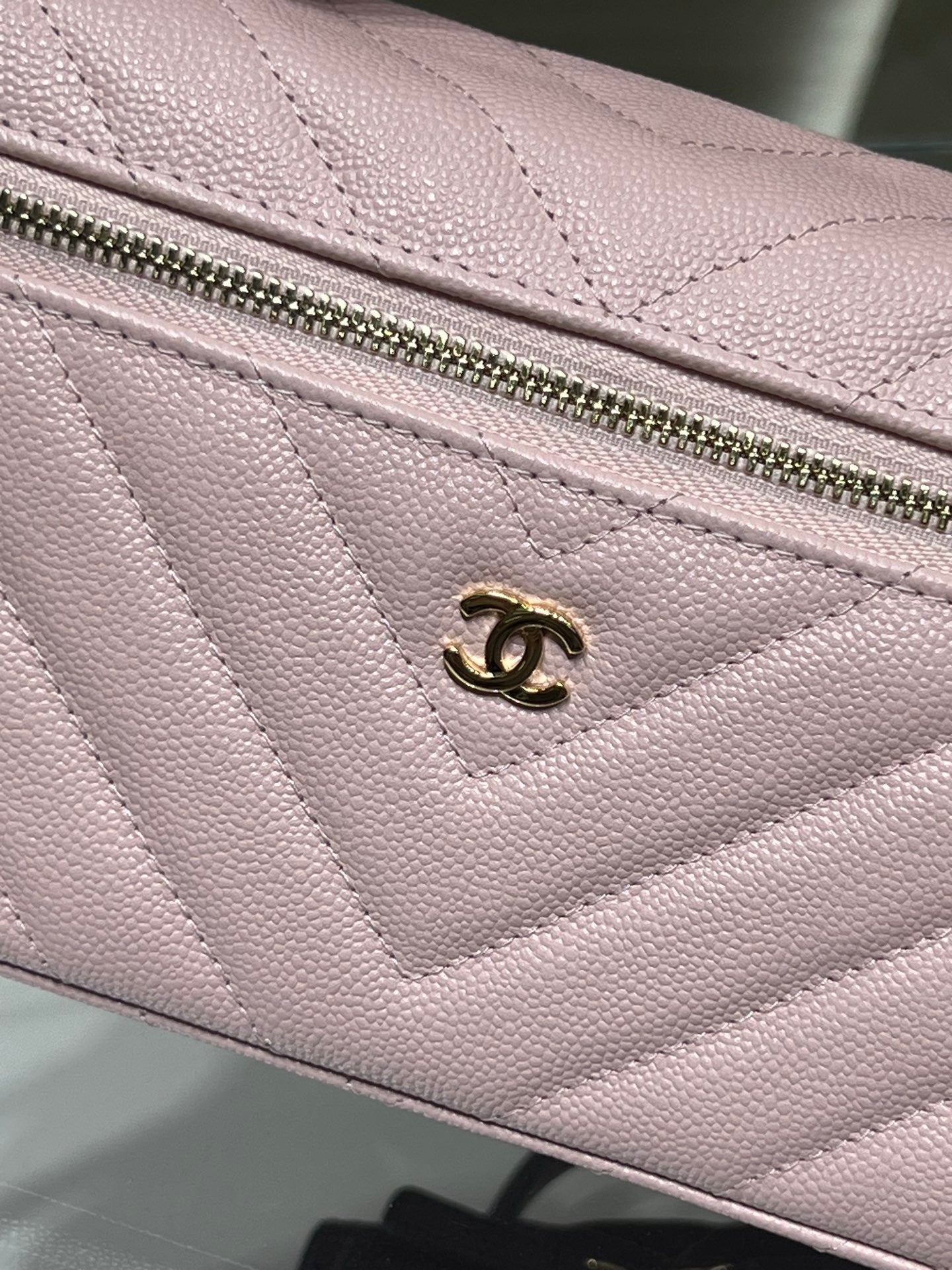 Pink quilted bag front panel with gold logo charm and zip pull