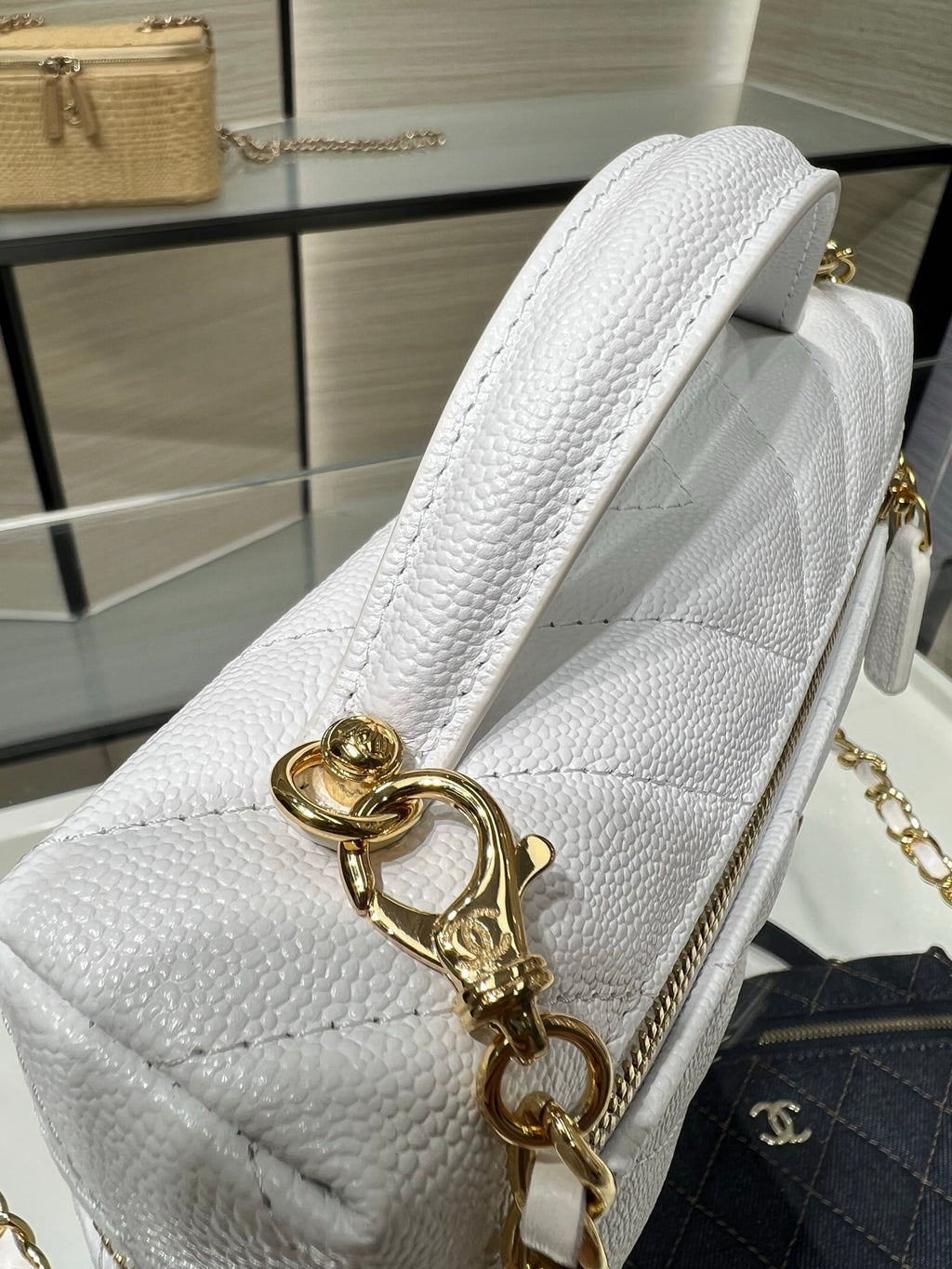 Chanel white leather bag close-up with gold clasp, chain handle, and textured side