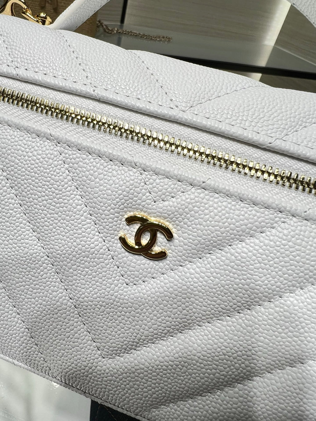 Chanel quilted white bag close-up with gold CC logo on flap