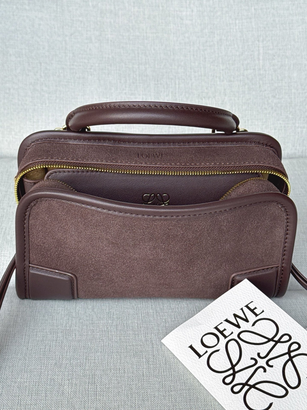 Loewe bag with top handle, adjustable strap, front pocket, and gold zipper trim.