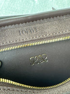 Loewe bag close-up showing embossed logo and gold zipper teeth on inner panel.
