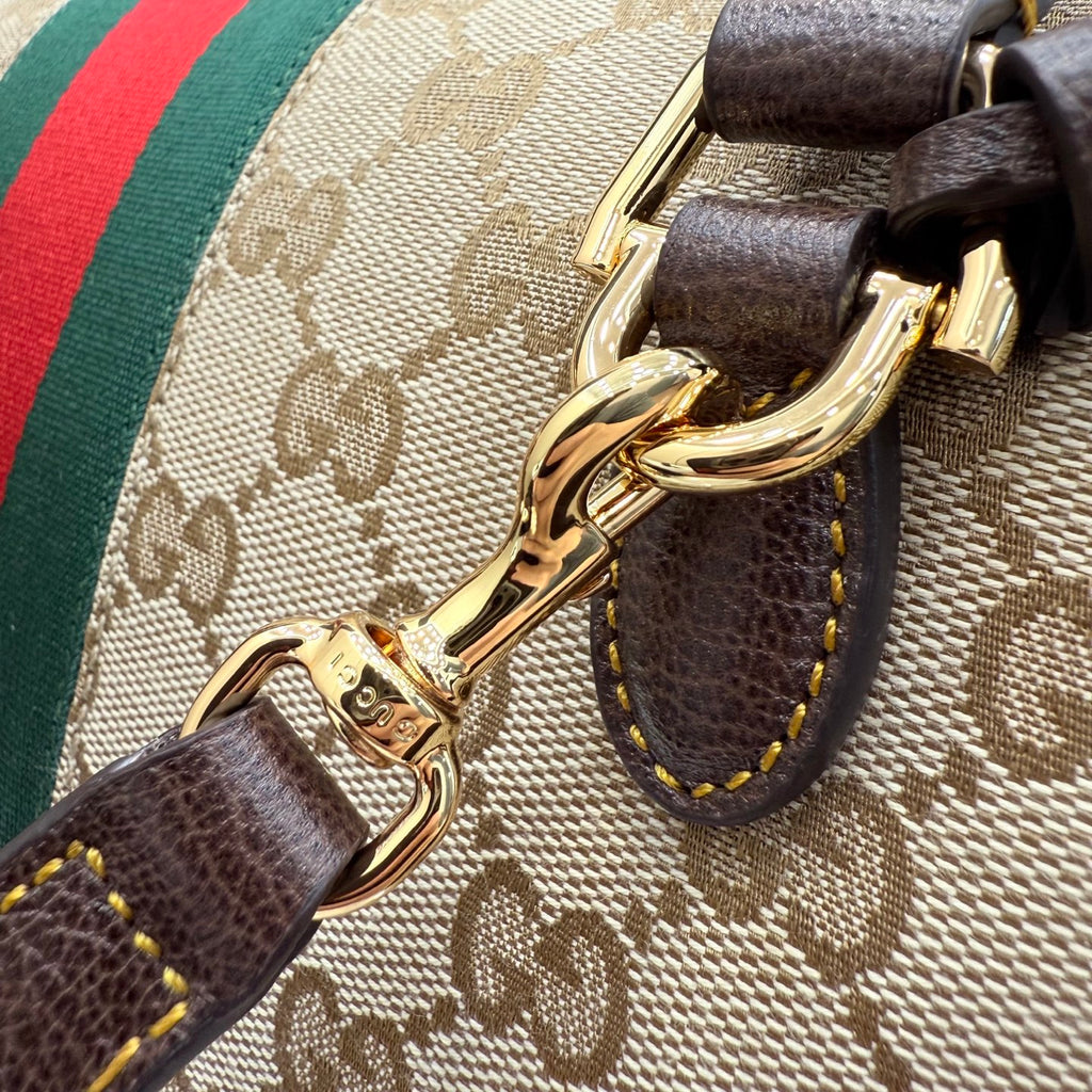 Gucci bag detail with dark leather strap and gold-tone hardware clips