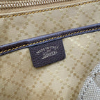 Fabric bag detail with blue trim stitching and leather brand patch reading "Gucci"