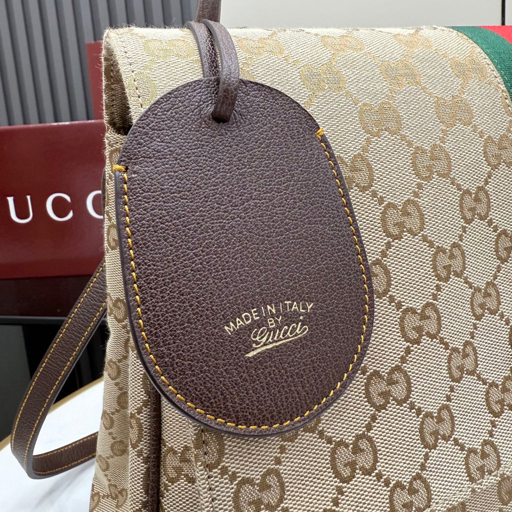 Gucci canvas bag with GG pattern and dark leather tag, leather strap visible