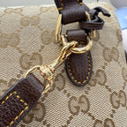 GG-print bag hardware close-up with gold-tone rings and brown leather strap attachment