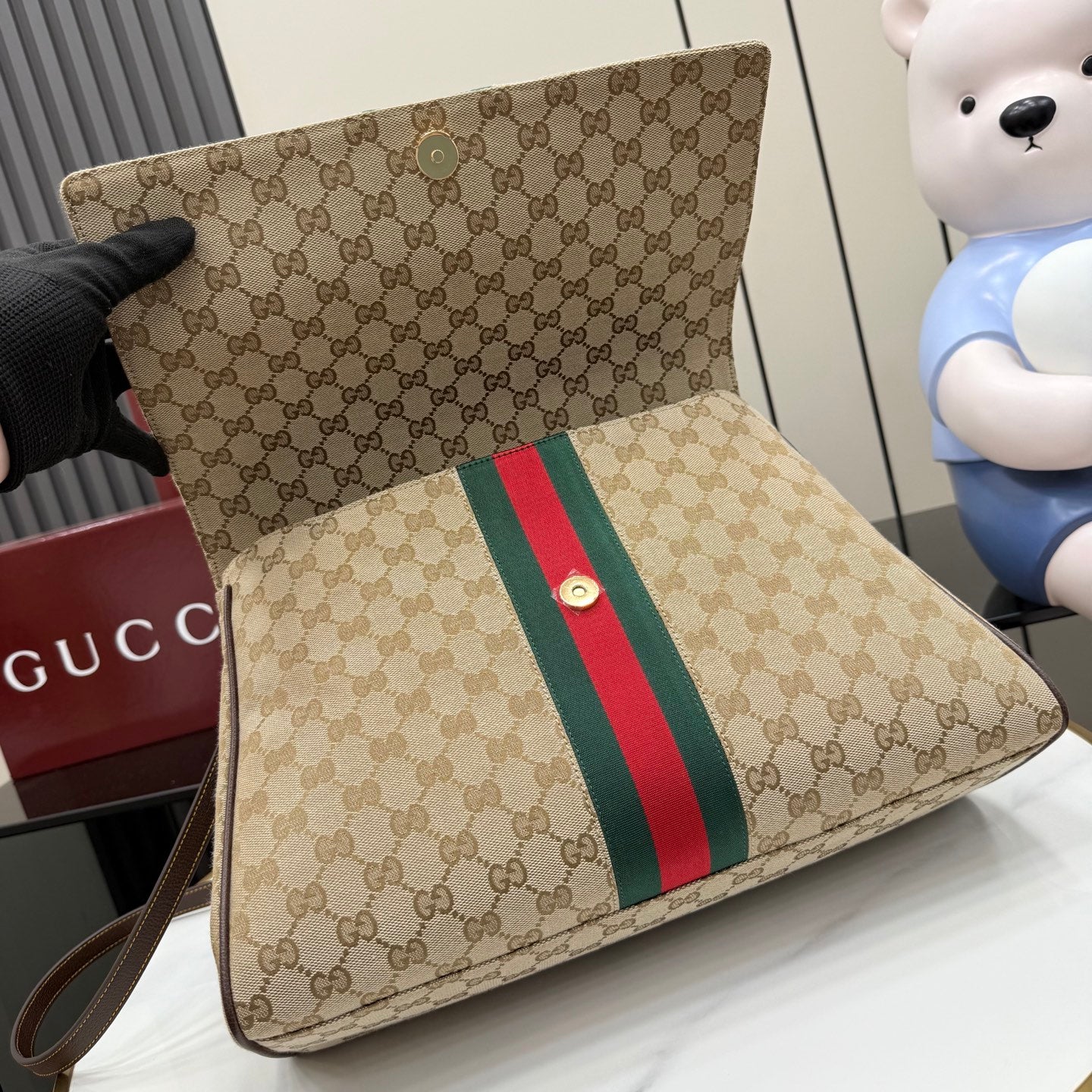 GG-print bag with green and red stripe on flap and front pocket, angled view