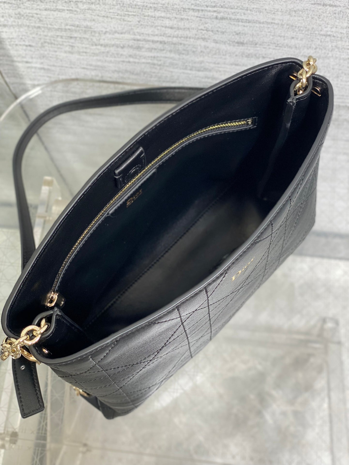 Dior textured leather crossbody bag interior view with gold zipper and chain strap.