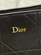 Dior logo patch on dark quilted leather bag front, stitched diamond pattern.