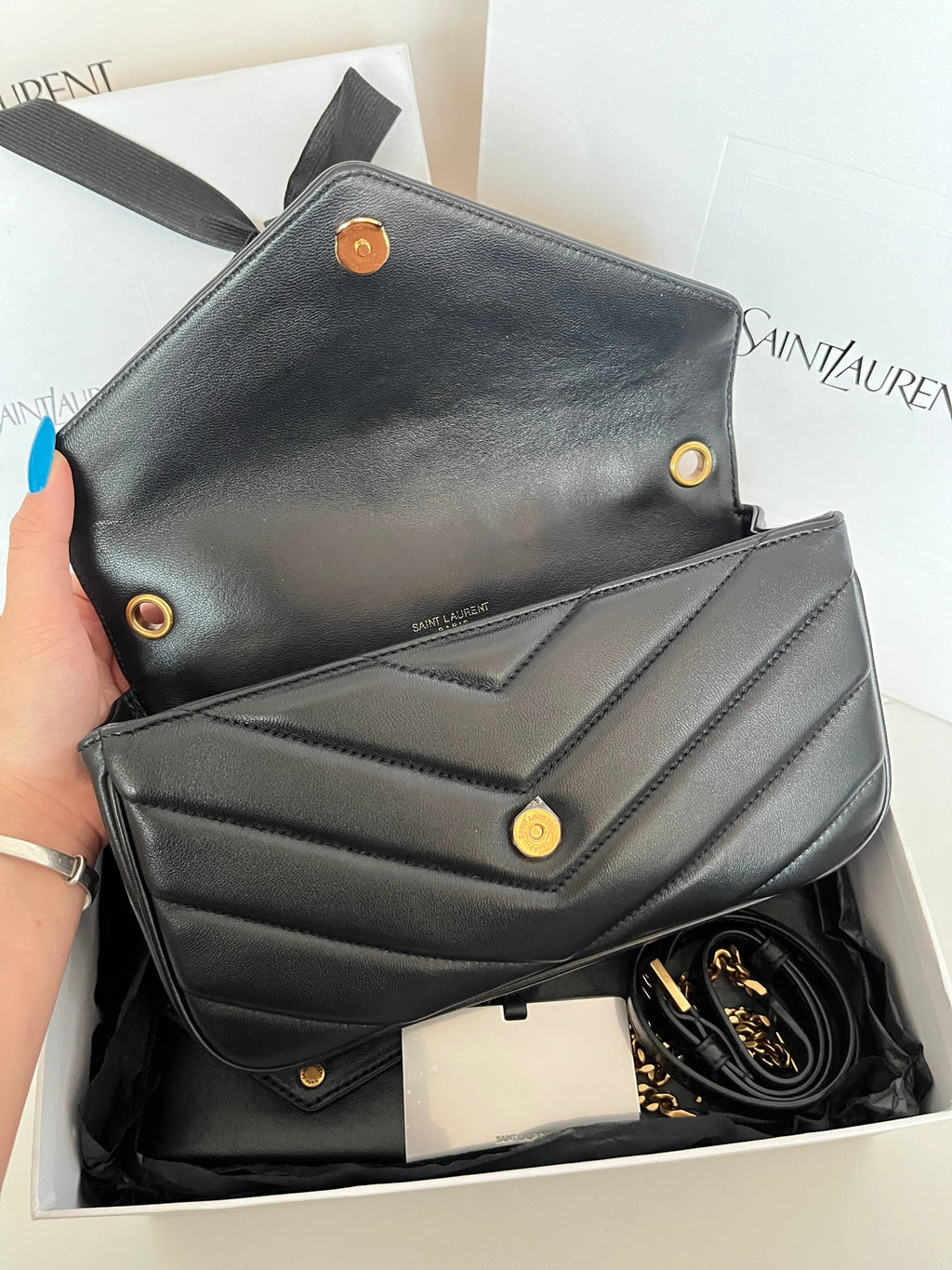 Dark gray leather YSL mini bag with flap front, gold snaps, and visible chain strap.