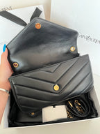 Dark gray leather YSL mini bag with flap front, gold snaps, and visible chain strap.