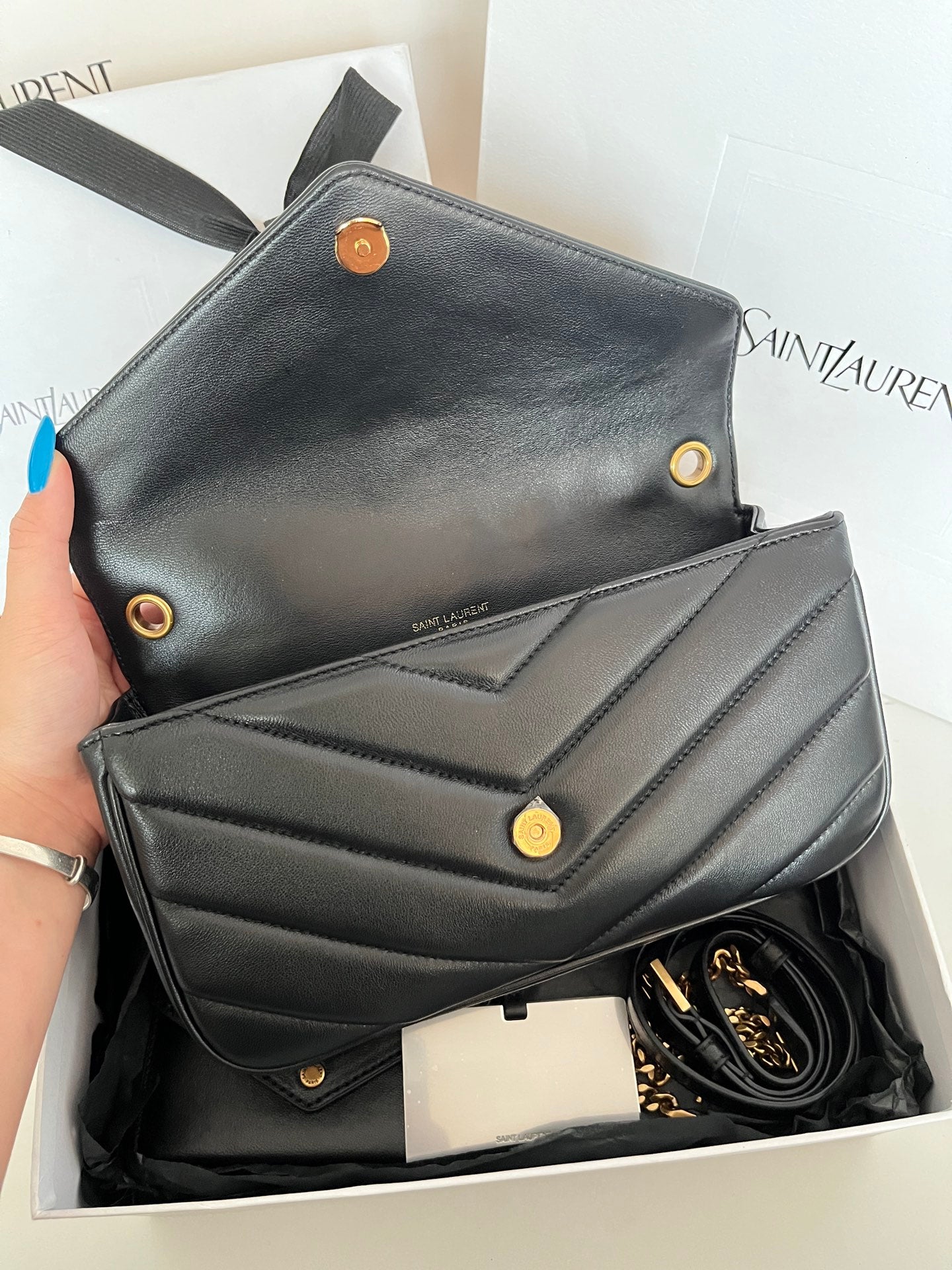Dark gray leather YSL mini bag with flap front, gold snaps, and visible chain strap.