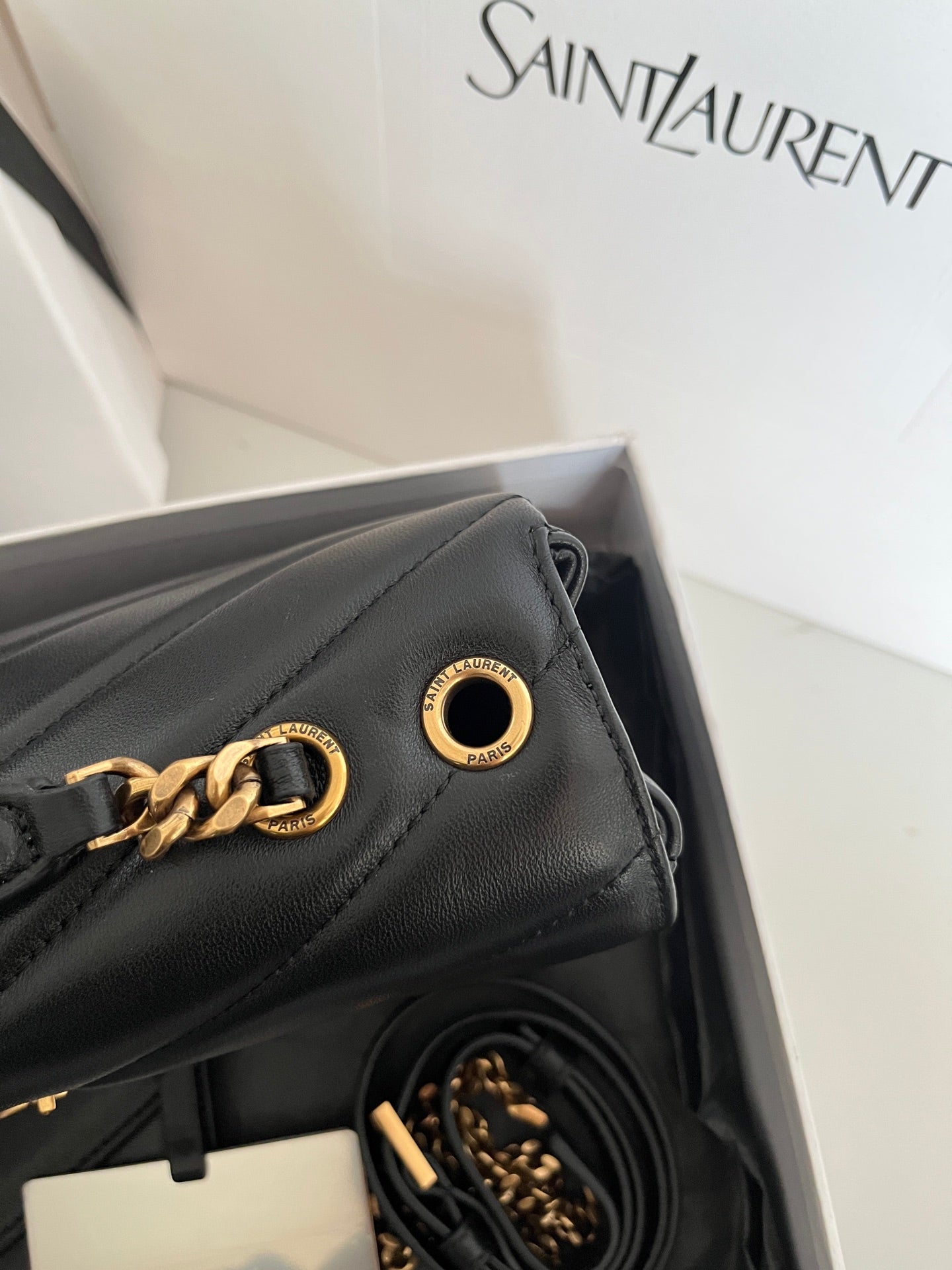 Dark gray leather YSL bag with gold chain hardware and ring clasp detail.