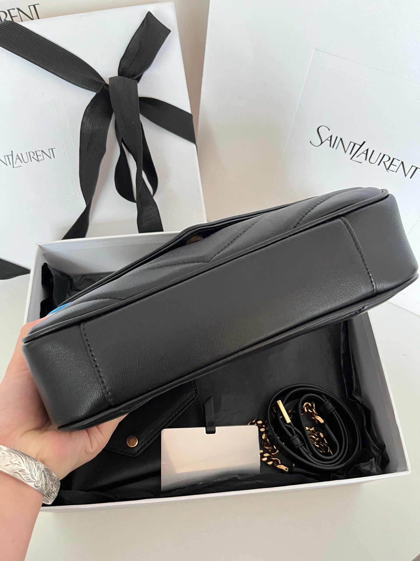Dark gray leather YSL bag with top handle, chevron flap, and gold-tone chain strap.