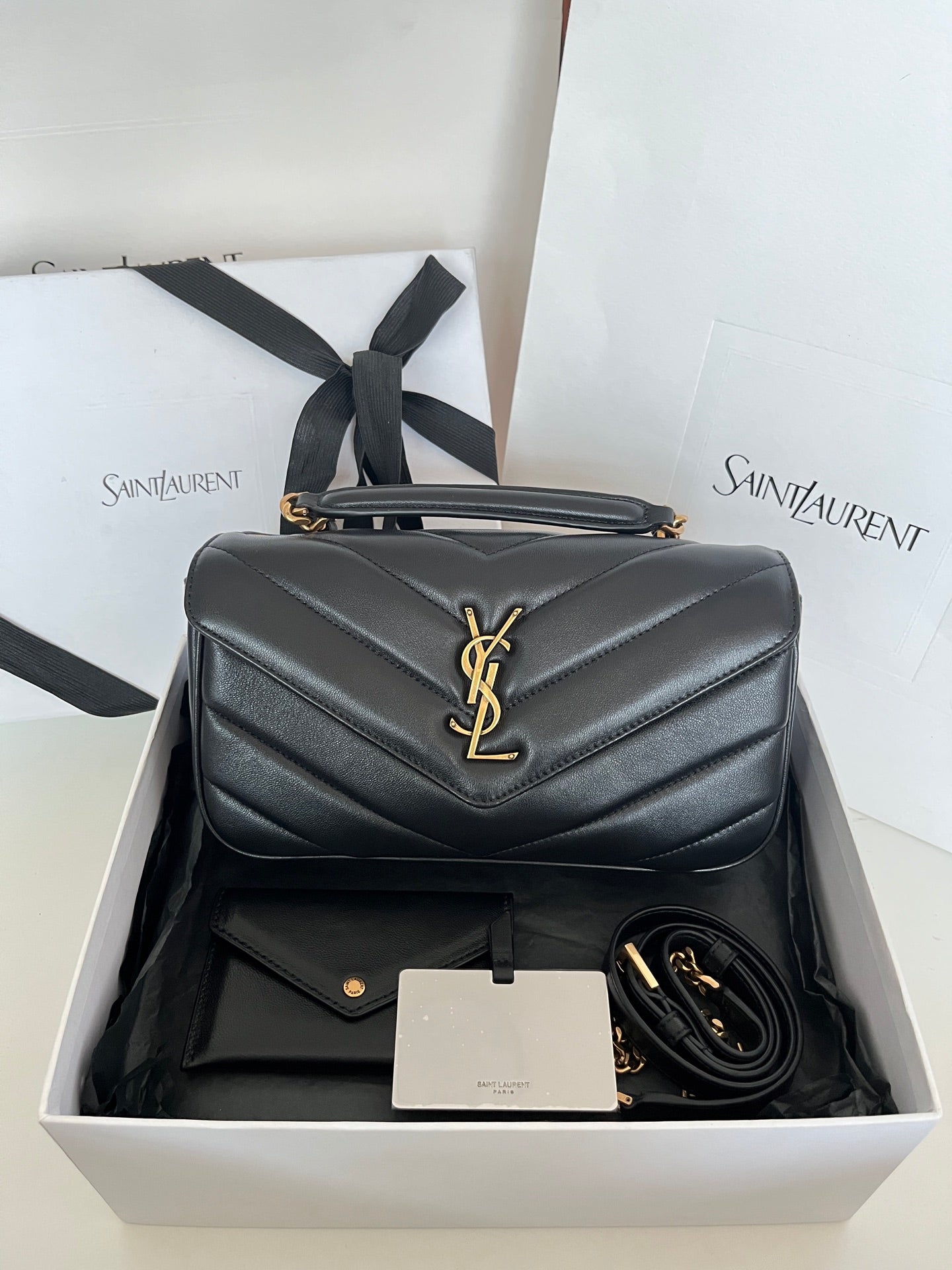 Dark gray quilted leather YSL bag with gold YSL emblem and top handle.