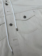 White jacket detail: snap placket, buttoned chest pocket and drawstring cords