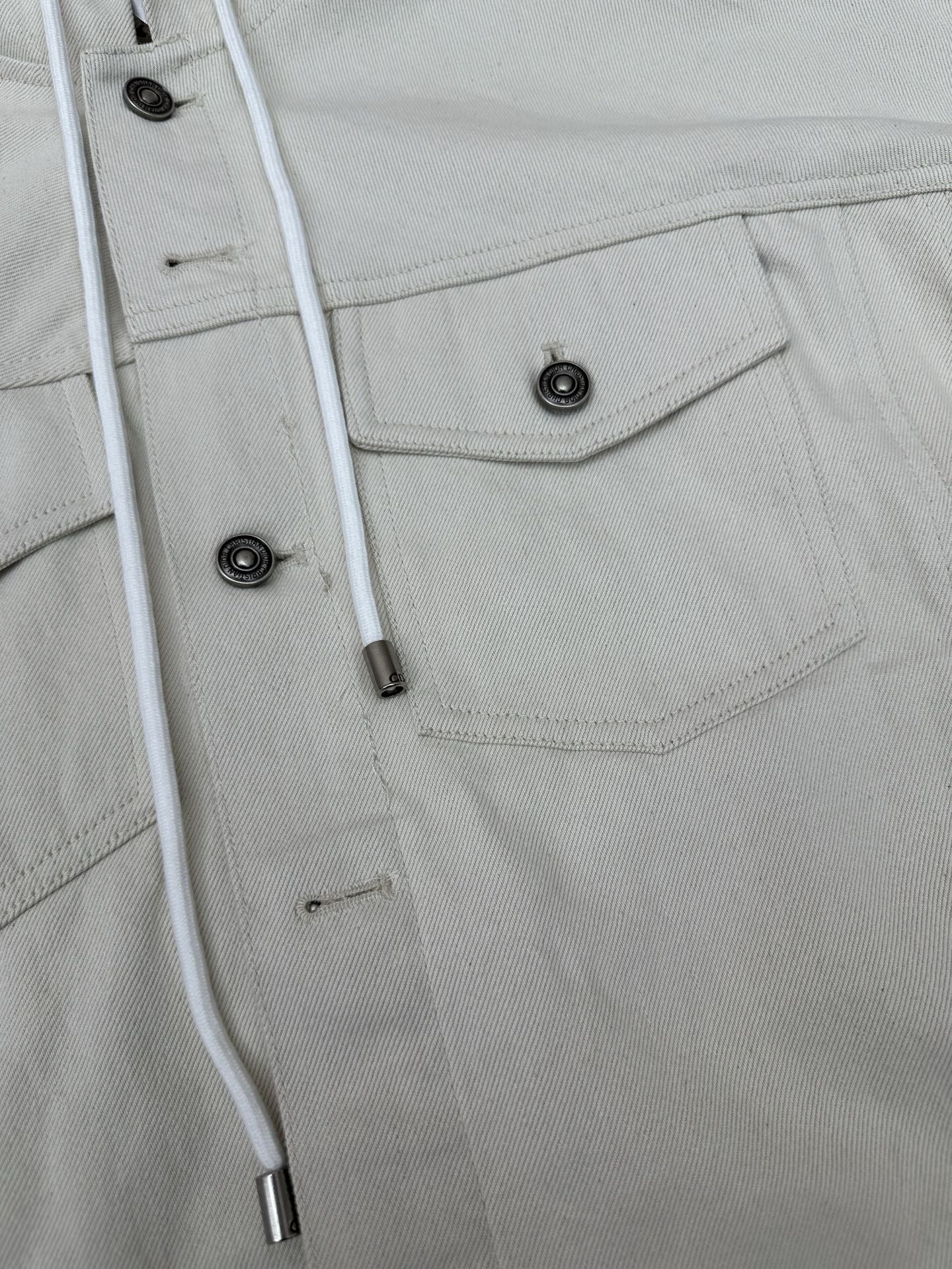 White jacket detail: snap placket, buttoned chest pocket and drawstring cords