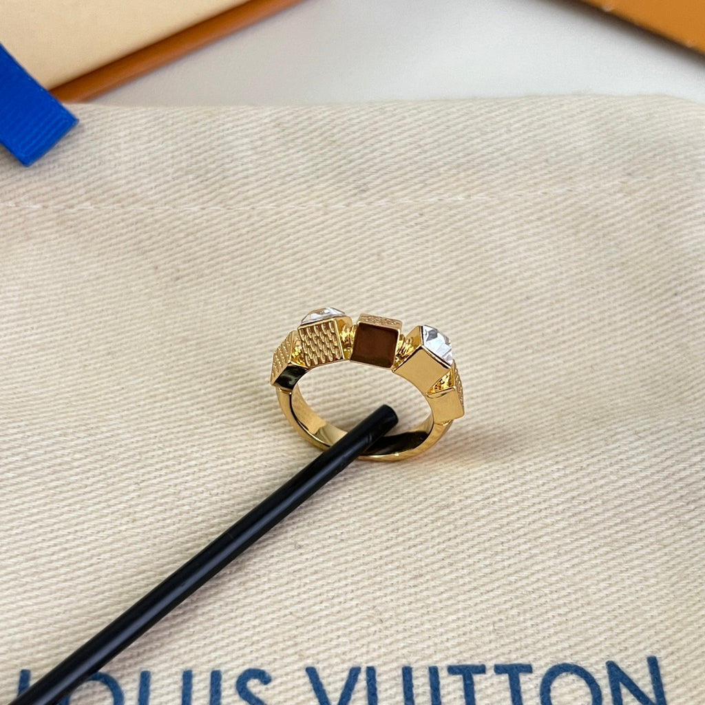 Gold-toned ring with clear stones on beige pouch with black leather strap