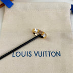Gold-toned ring with clear stones on beige pouch with Louis Vuitton logo