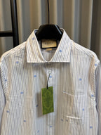 Long-sleeve light striped shirt with blue dot motifs, button placket, and green tag