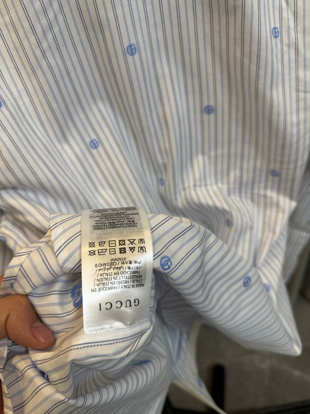 Collar and care label of a light striped long-sleeve shirt with blue dot motifs