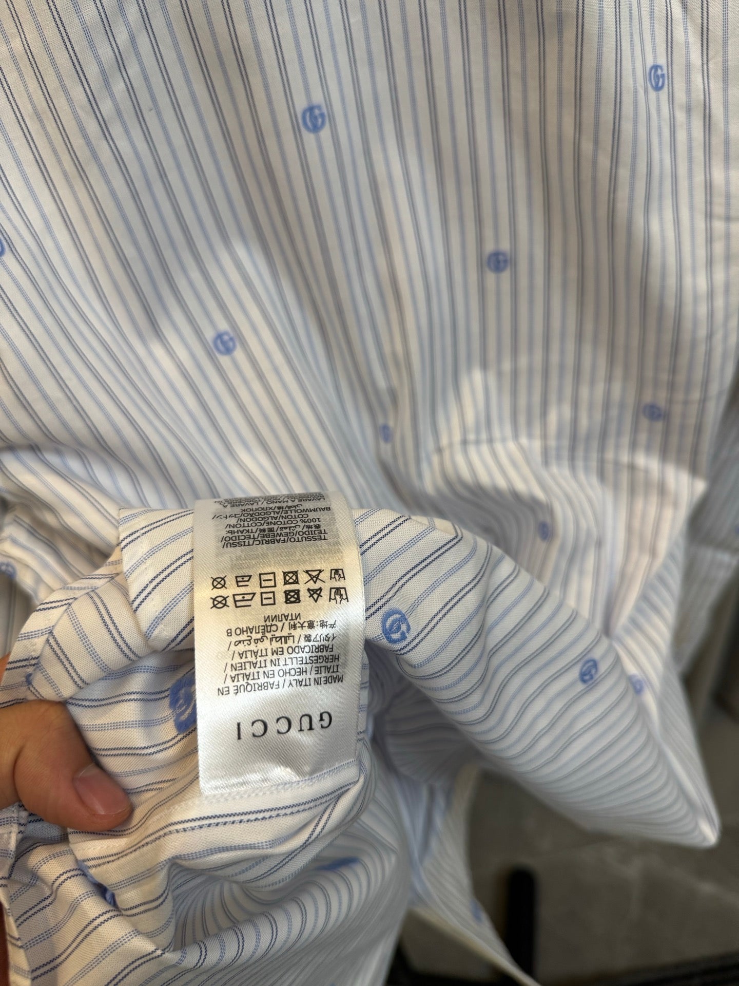 Collar and care label of a light striped long-sleeve shirt with blue dot motifs