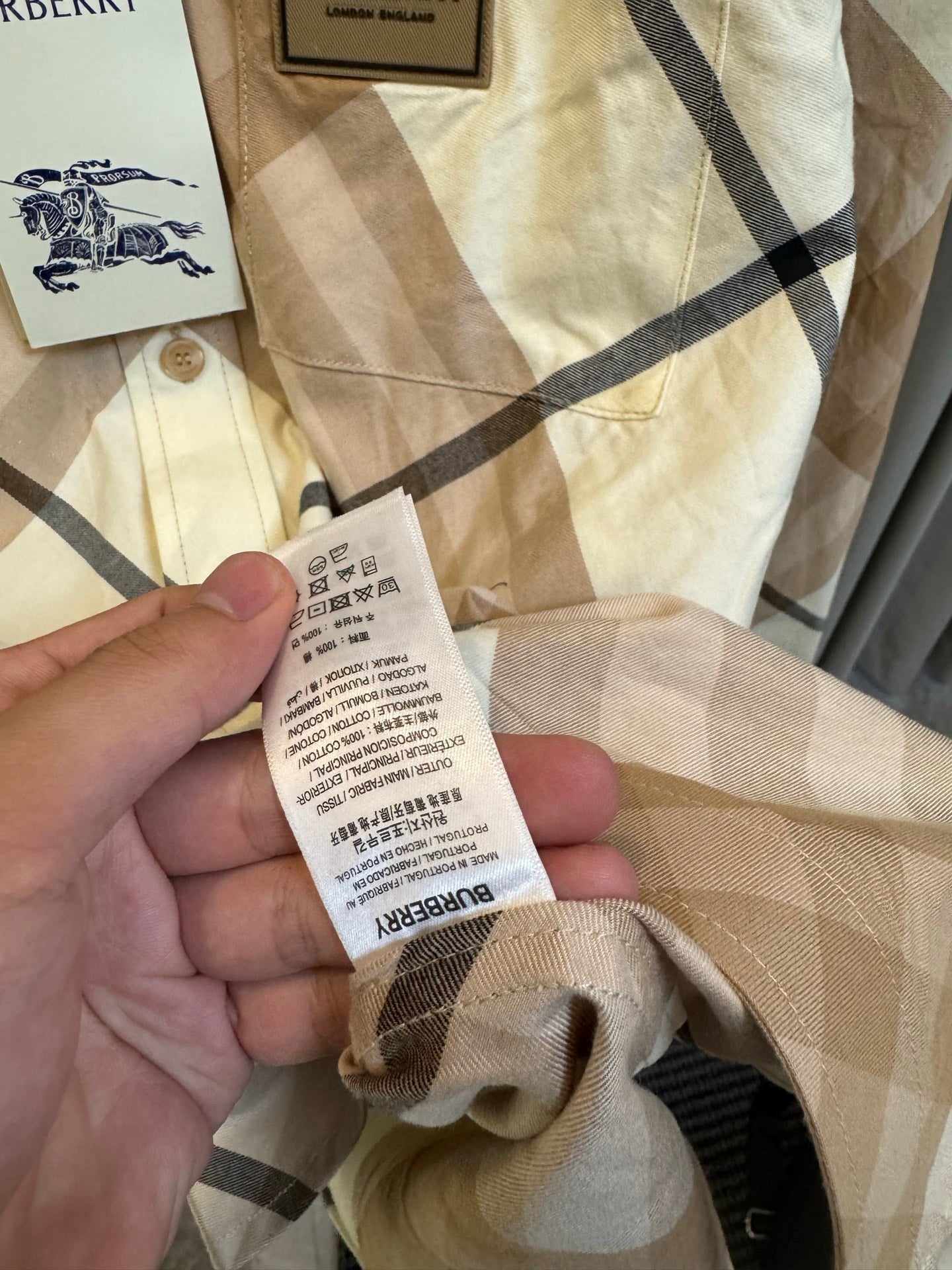 Burberry check shirt care label close-up on beige and navy plaid fabric