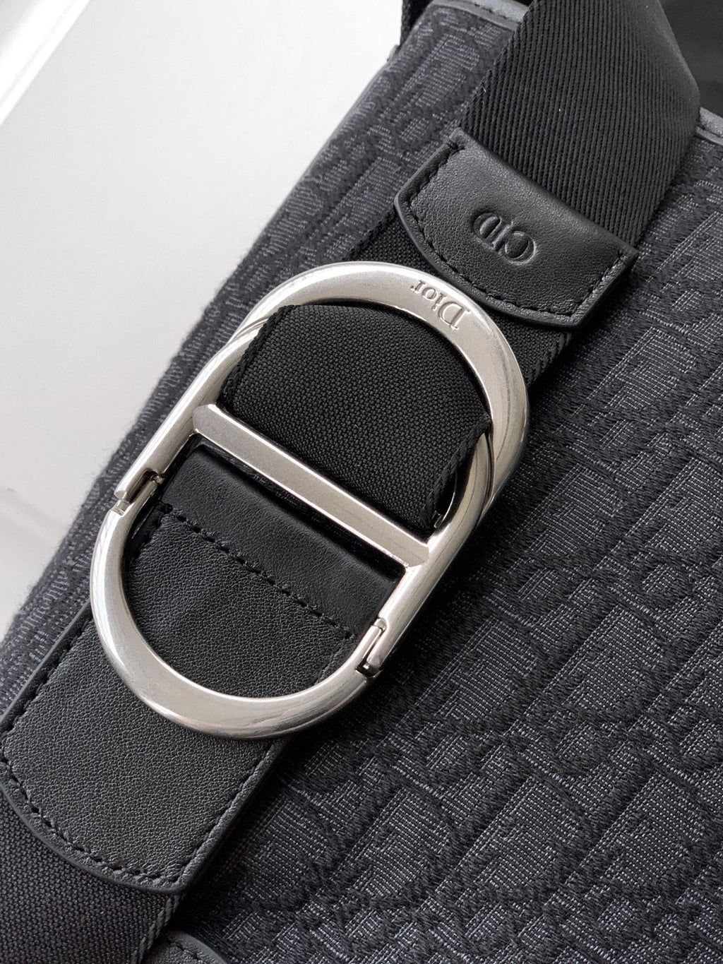 Dior strap detail on dark bag: silver O-ring and textured logo webbing