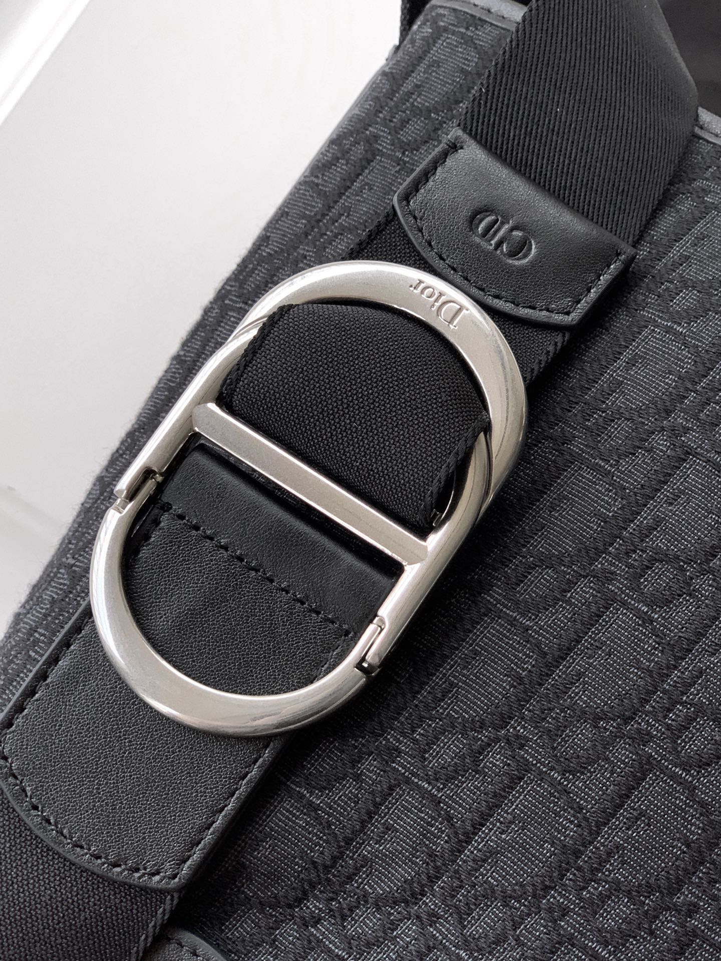 Dior strap detail on dark bag: silver O-ring and textured logo webbing