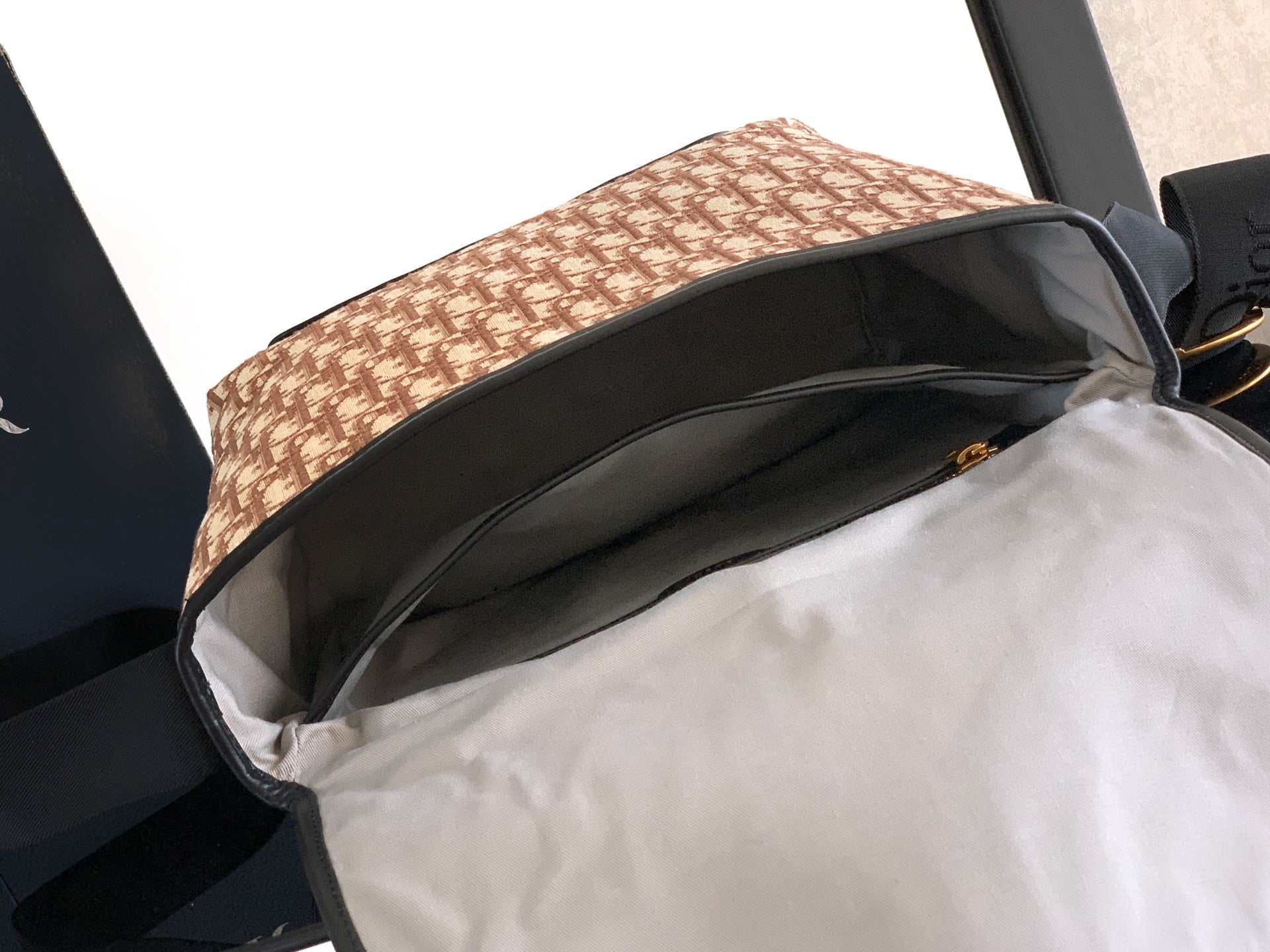 Dior bag open view: beige patterned top with black trim and light interior lining