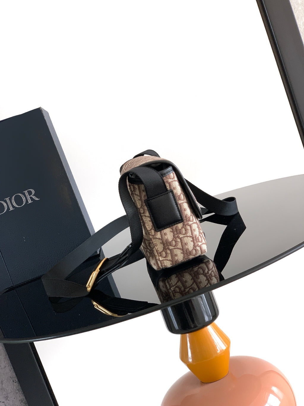 Dior mini crossbody bag angled view, beige monogram canvas with black strap