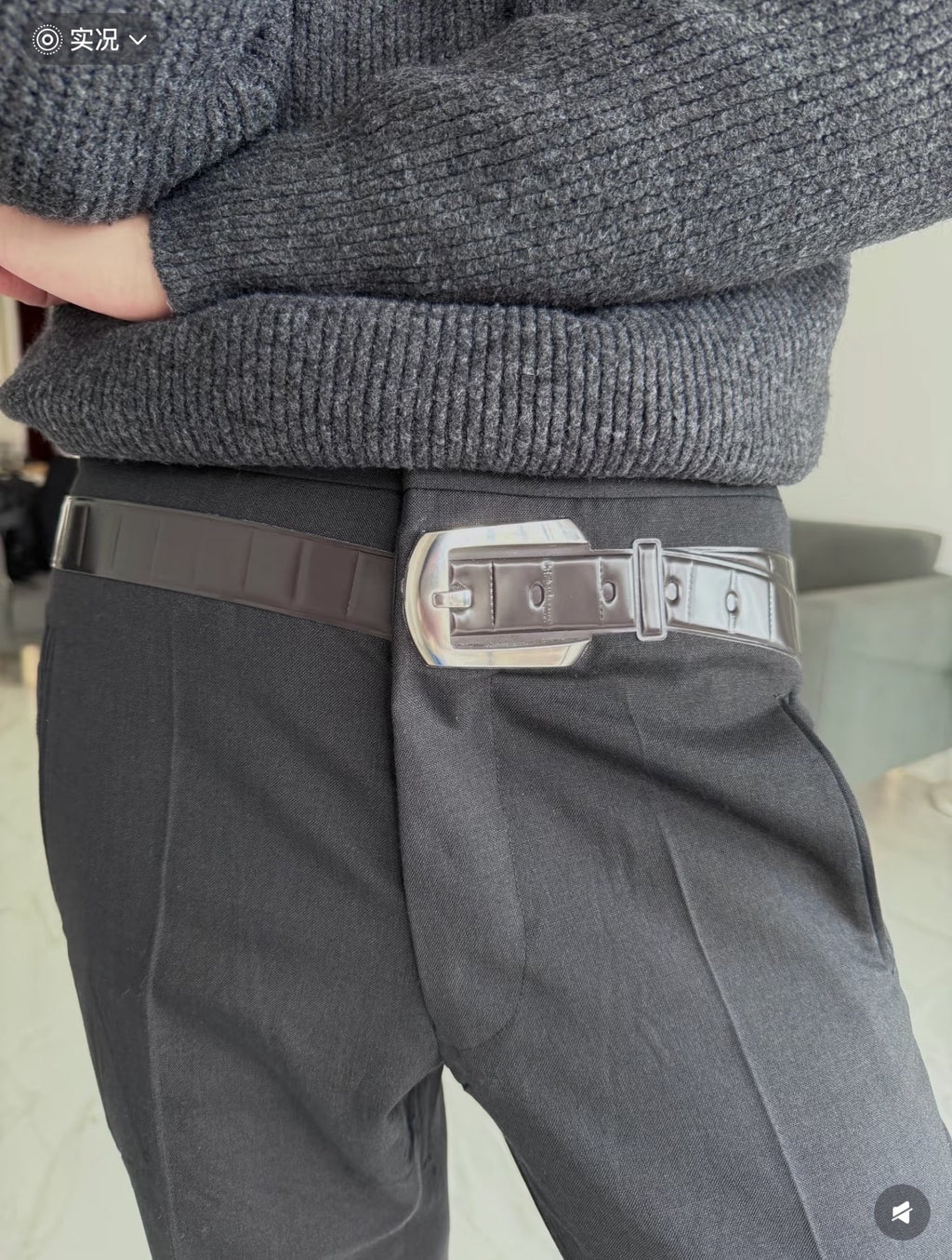 Dark gray pants with pleats and adjustable belt; straight-leg fit