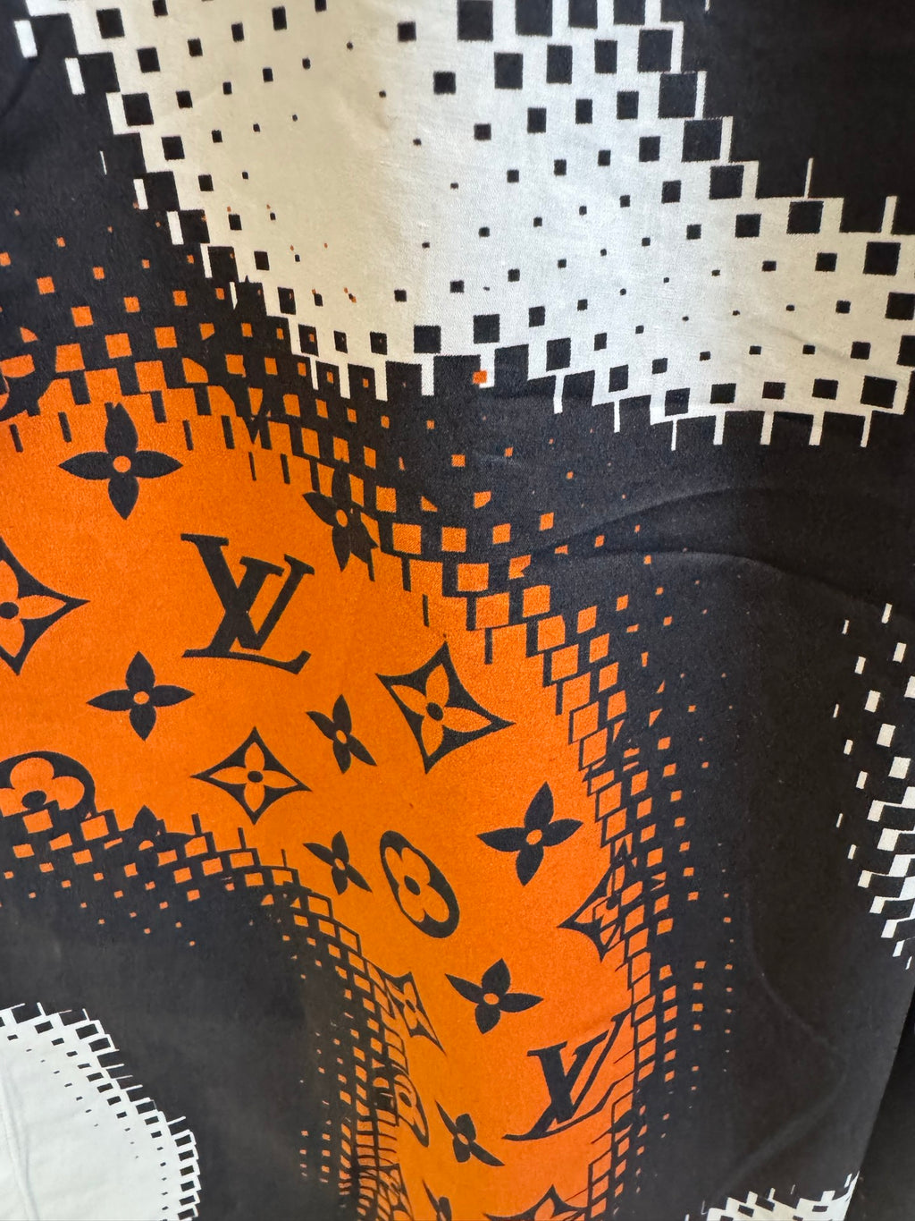 Louis Vuitton fabric detail with orange-and-black monogram pattern and dotted pixel effect