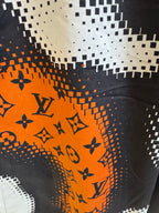 Louis Vuitton fabric detail with orange-and-black monogram pattern and dotted pixel effect