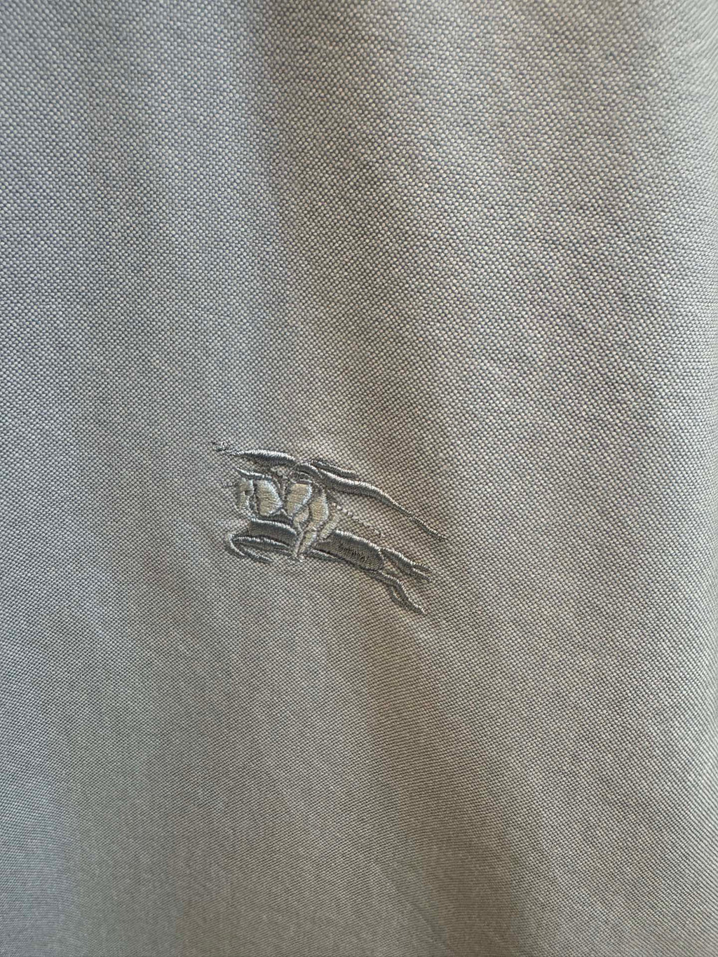 Embroidered horse logo on light blue Burberry shirt fabric