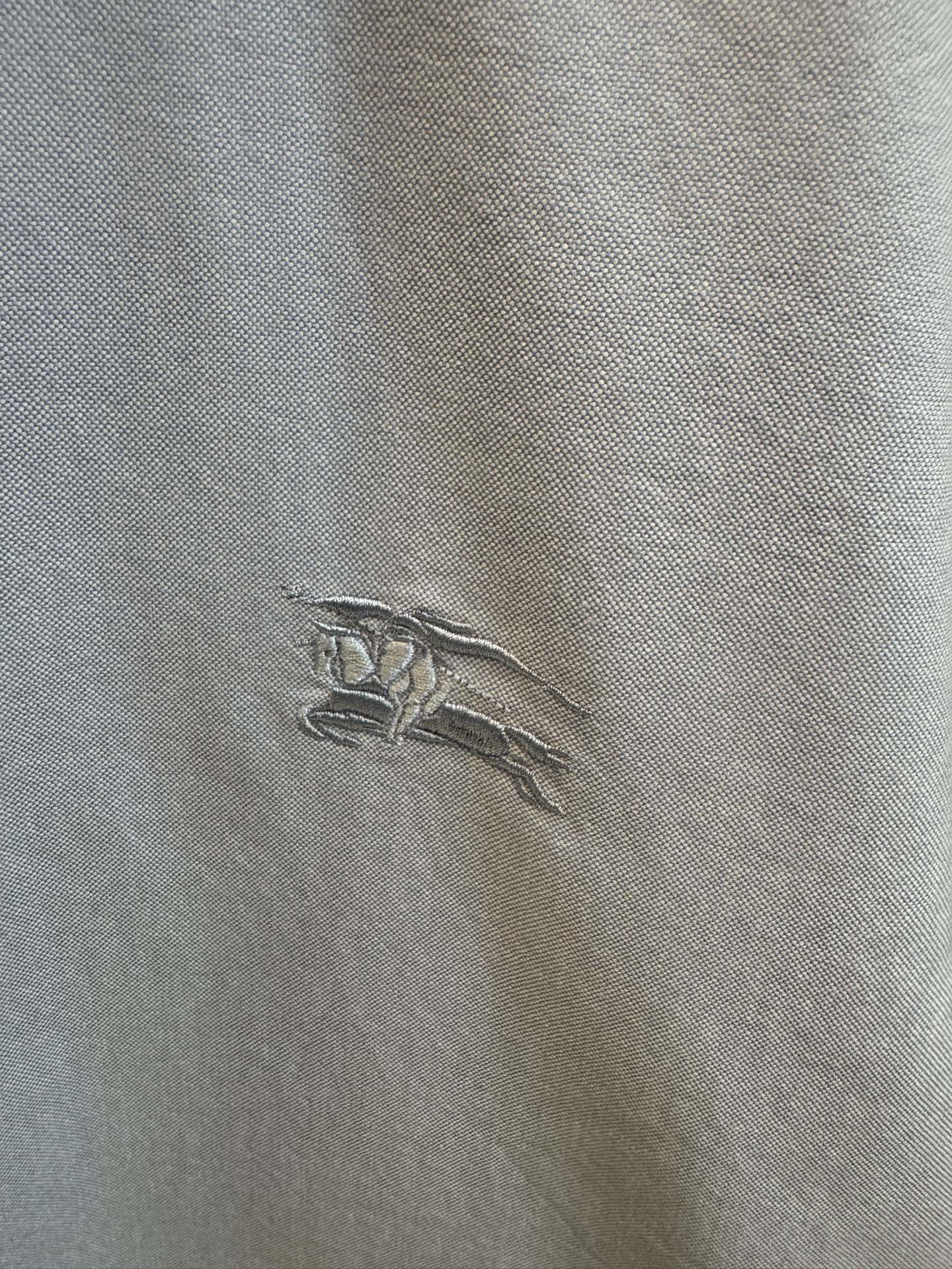 Embroidered horse logo on light blue Burberry shirt fabric
