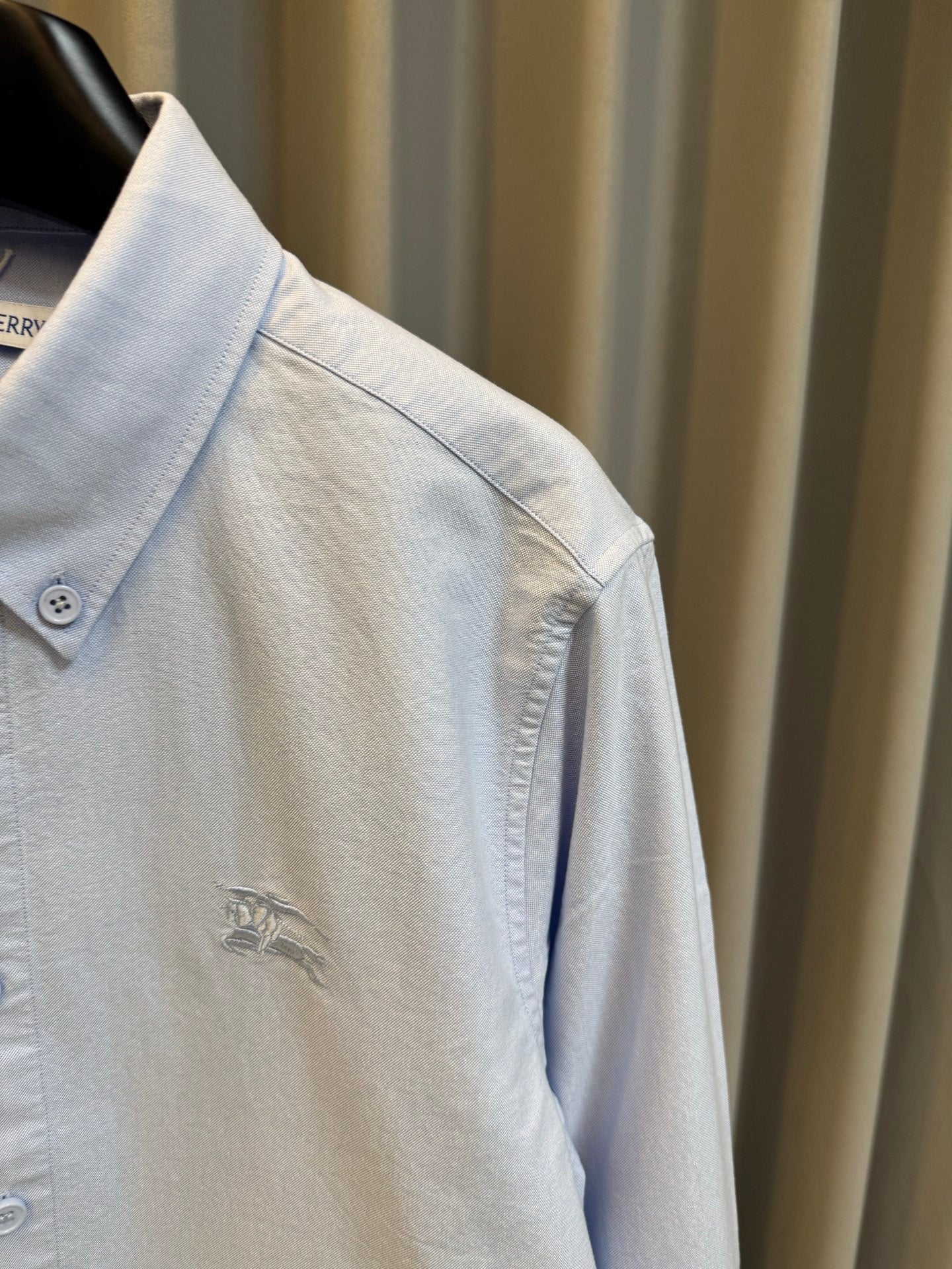 Light blue Burberry button-up shirt sleeve with small embroidered horse logo