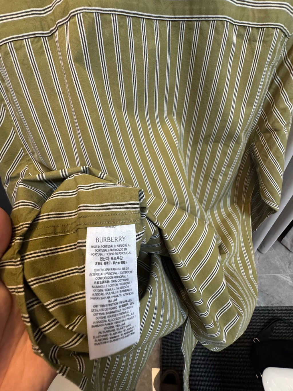 Green striped shirt tag on interior neck area with draped fabric