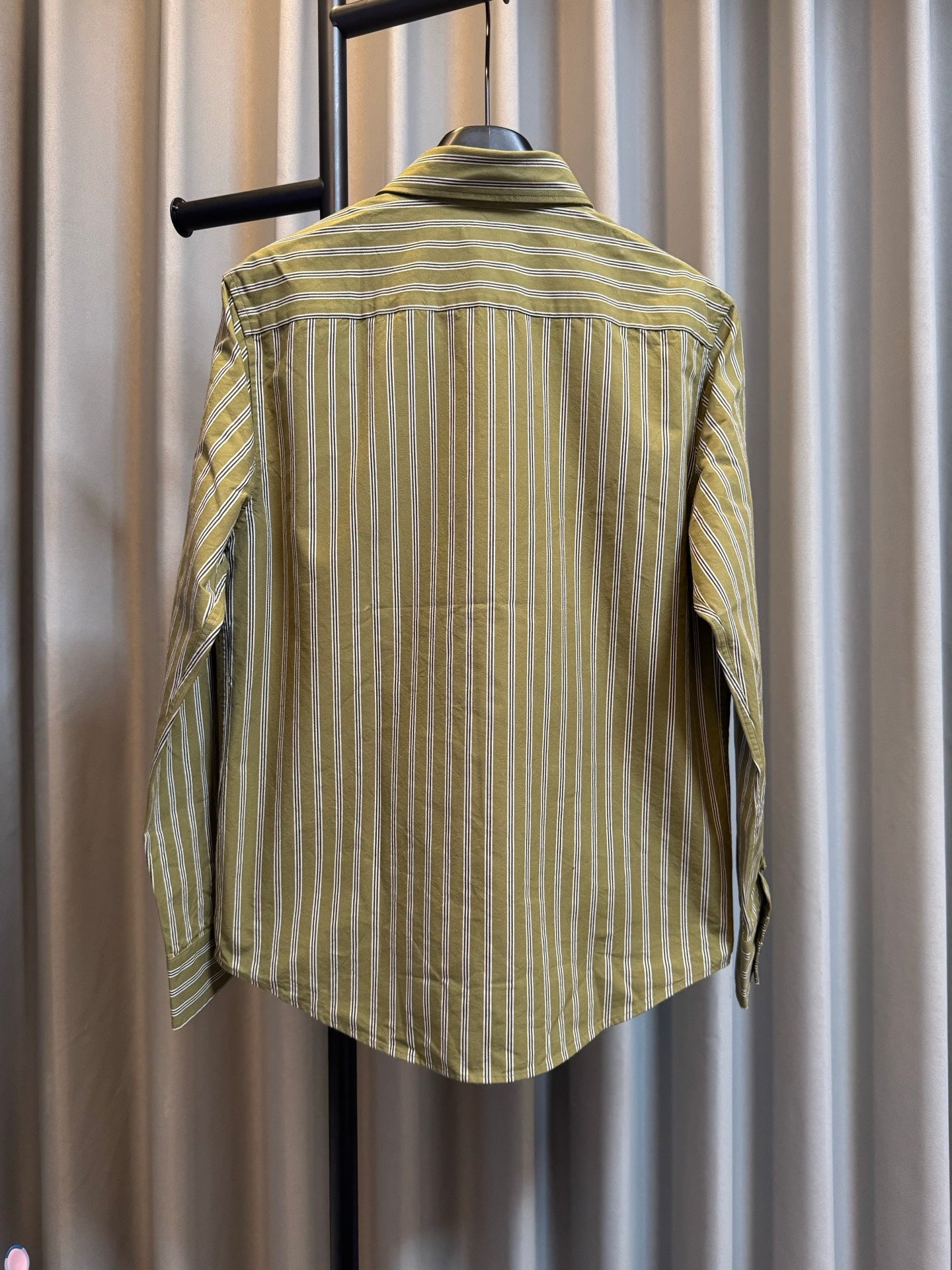 Back view of green striped button-up shirt on hanger