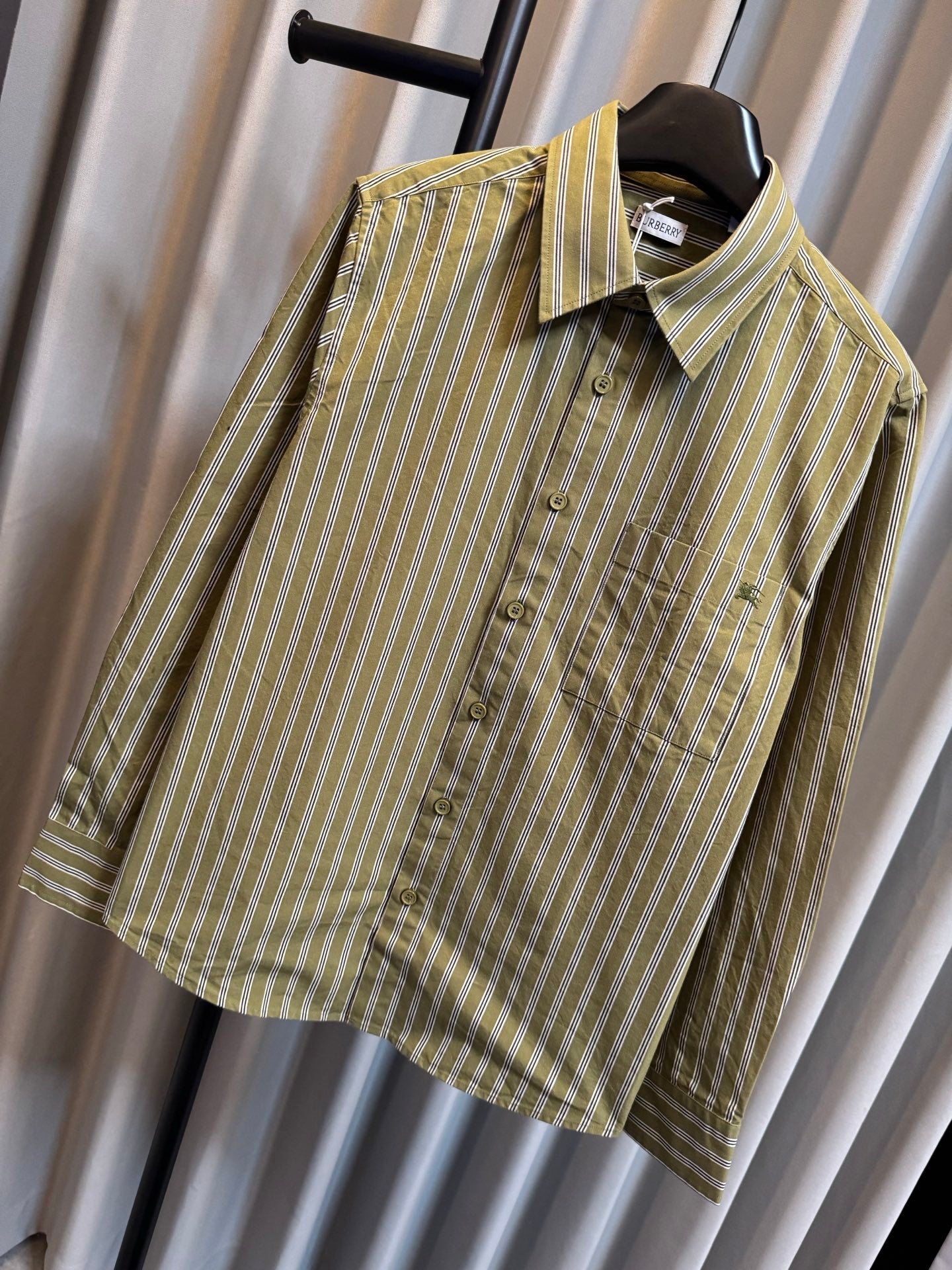 Side view of green striped button-up shirt on hanger