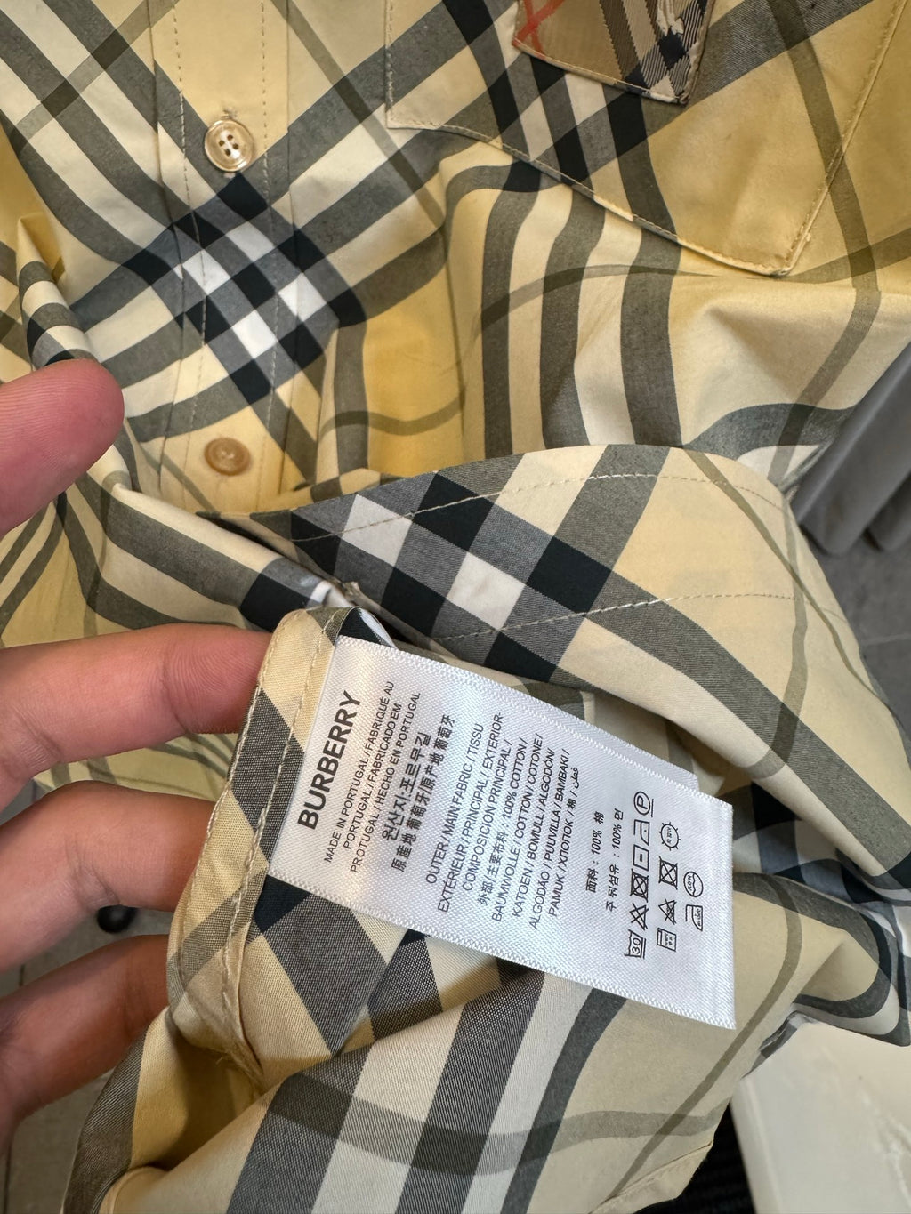 Burberry clothing care label in neck area inside tan and navy plaid shirt