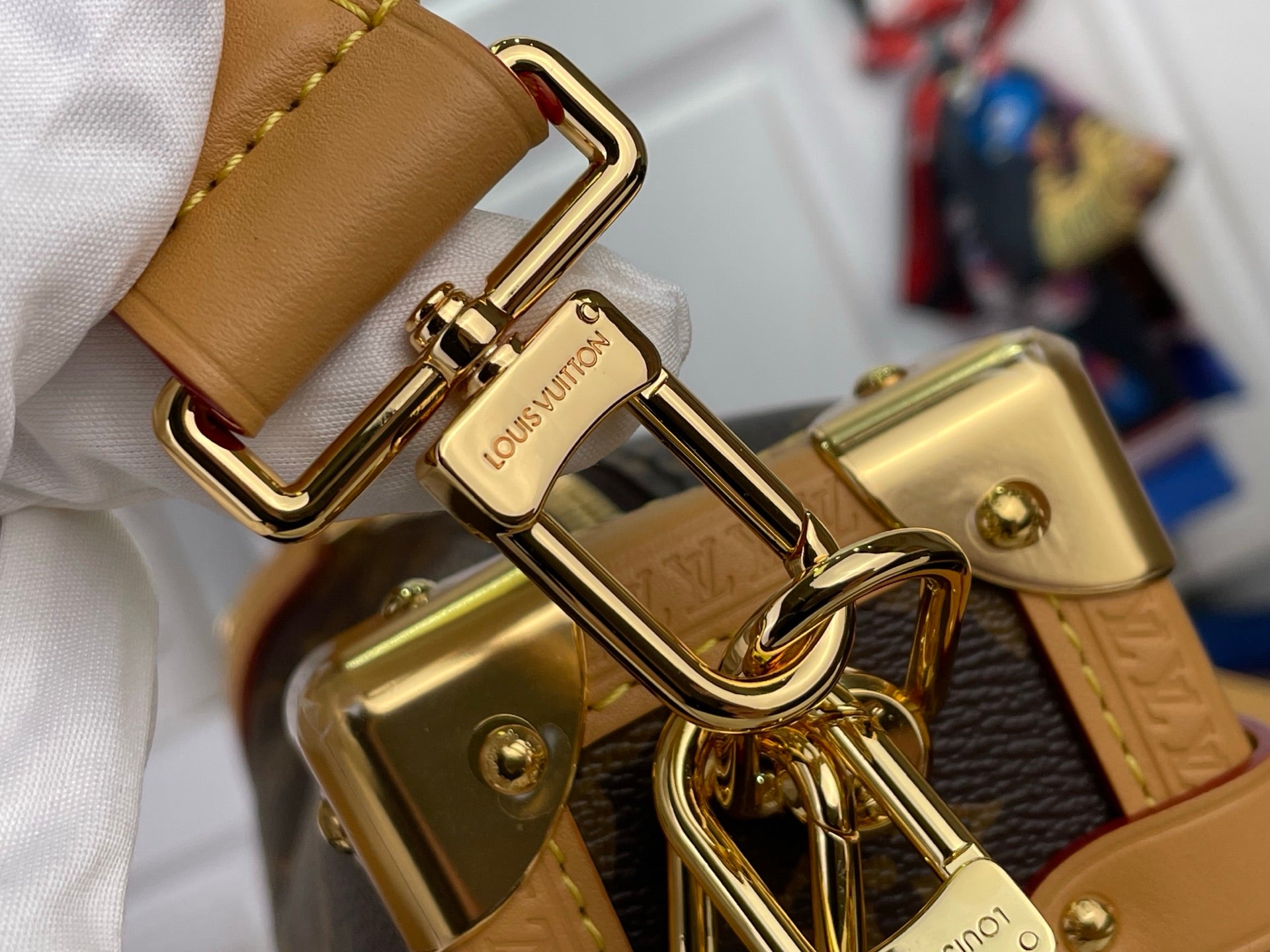 Louis Vuitton monogram bag close-up of gold D-ring and tan leather strap