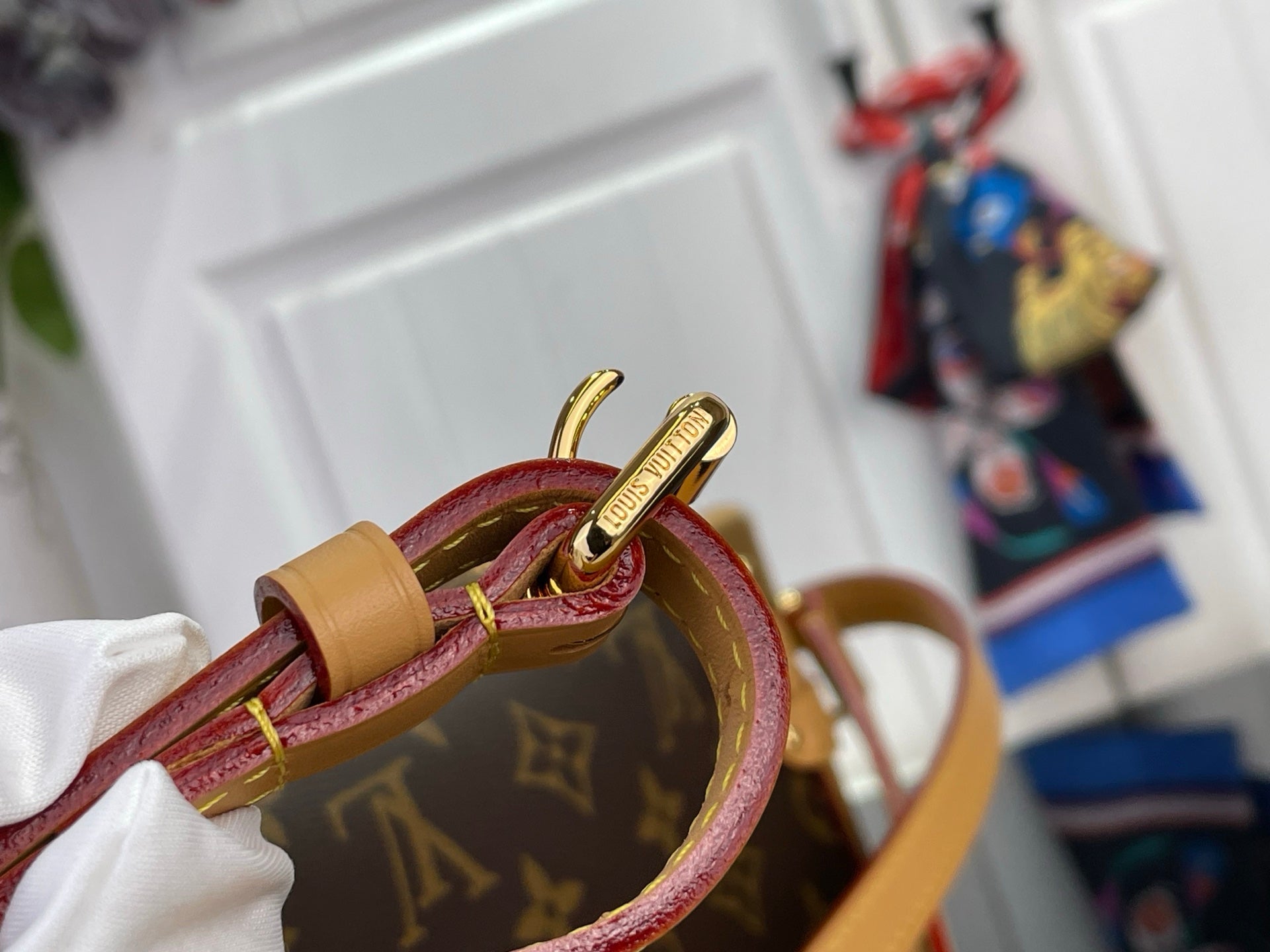 Louis Vuitton monogram bag close-up of burgundy strap and tan leather loop